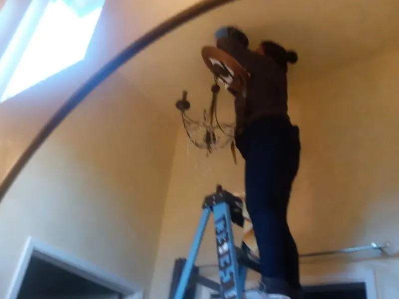 Electrician installing a chandelier in a Kingfisher residence